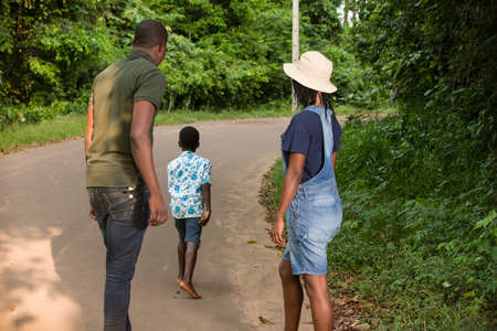 young couple standing in a park watching their child run.の写真素材