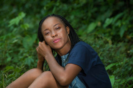 young woman sitting in a park adjusting her earring.の写真素材