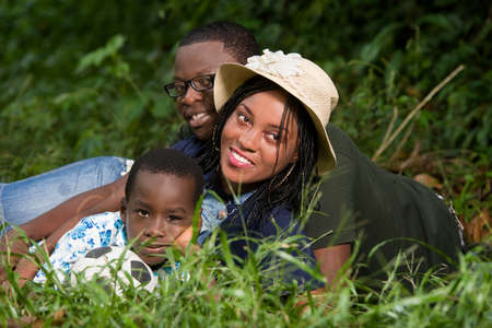 young family lying in a park watching the camera smiling.の写真素材