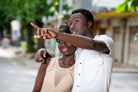 Young happy couple kissing on the street. Happy man shows away from must to his loverの写真素材