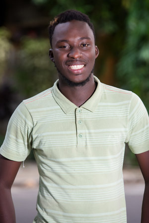 young african man standing outdoors looking at camera smiling.