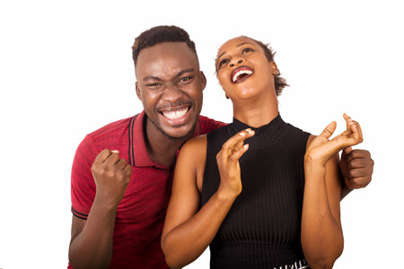 young couple standing on white background laughing while looking at the camera.の写真素材