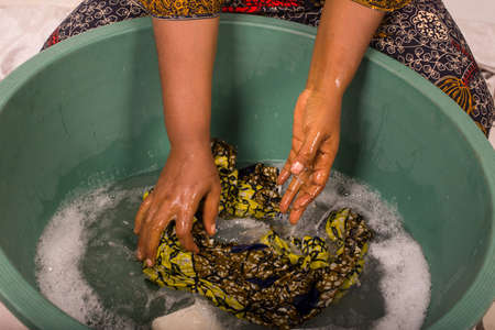 mature african woman in loincloth sitting doing laundry.の写真素材