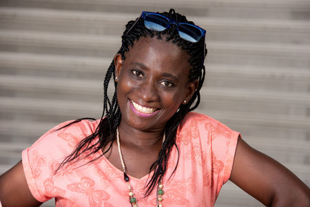 young woman standing with sunglasses looking at camera smiling.