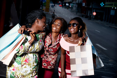 group of young women standing outdoors laughing while holding shopping bags.の写真素材