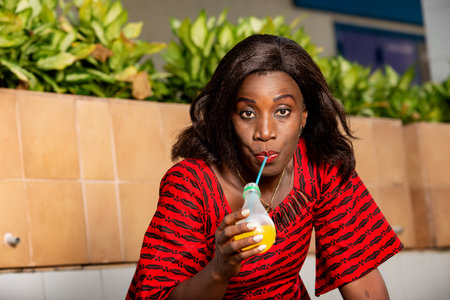 mature woman sitting outdoors drinking fruit juice while looking away.