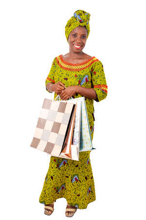 beautiful african adult woman wearing a loincloth and a green scarf is smiling and happy with shopping bagsの写真素材