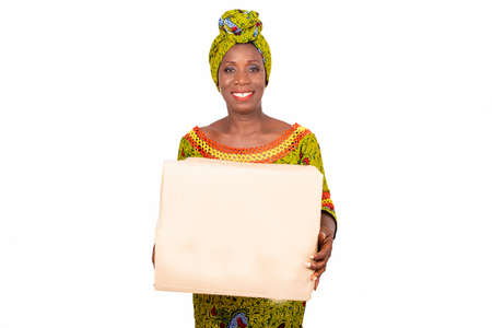 beautiful African adult woman wearing a loincloth and a green scarf in her head, smiling standing holding a cardboard bagの写真素材
