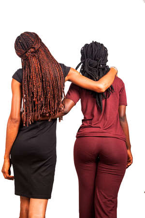 two beautiful young friends standing with long braids on their backsの写真素材