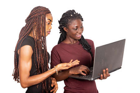 young beautiful sisters standing sideways working with a laptop computer smilingの写真素材