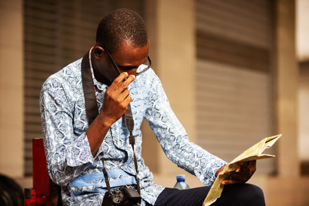 rear view of a young tourist man wearing a shirt in a jeans holding a map in his handの写真素材