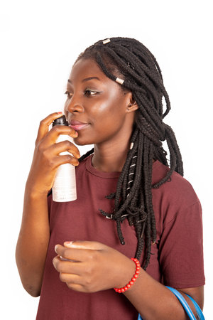 young woman standing smelling a perfume while smiling isolated on white backgroundの写真素材