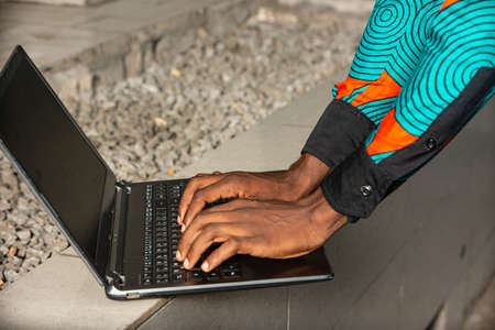 adult male hand typing laptop in the streetの写真素材