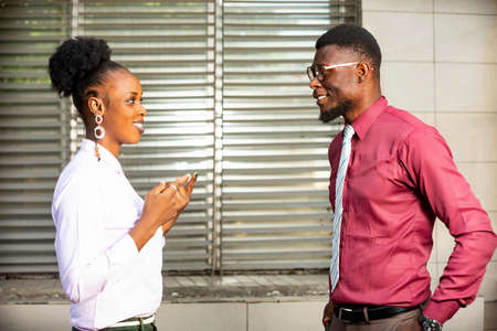 businessman and businesswoman standing and talking together near the office of the business center smilingの写真素材