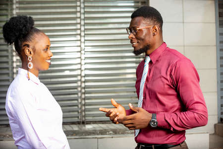 businessman and businesswoman standing and talking together near the office of the business center smilingの写真素材