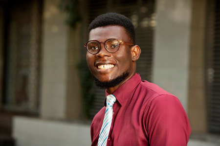 Portrait of a young student walking on the street. The beauty of men, wearing glasses all happy clothe with a red chemise and tieの写真素材