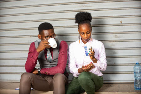 young business people sitting outside and drinking a cup of coffeeの写真素材