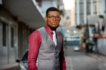 portrait of a serious young man wearing glasses and walking in the street and looking at the camera