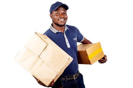 young delivery man standing in hat on white background carrying cardboard boxes smiling.の写真素材