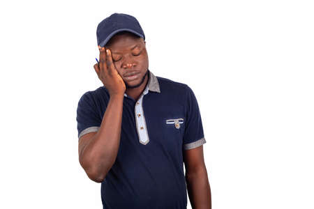 tired, young delivery man standing asleep and putting his hand on the cheek with his eyes closedの写真素材