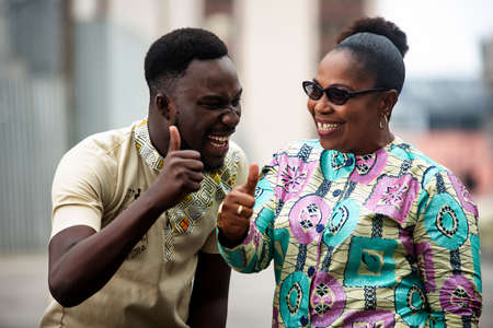 happy two people raising together thumbs up with fingers being all smilingの写真素材