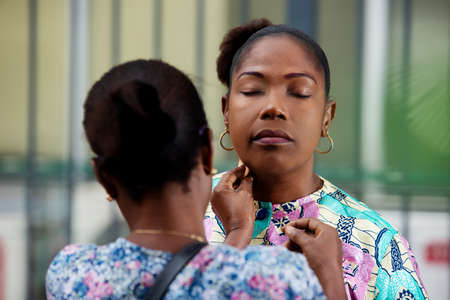 beautiful adult woman getting makeup done by professional make-up artist outdoors on the streetの写真素材