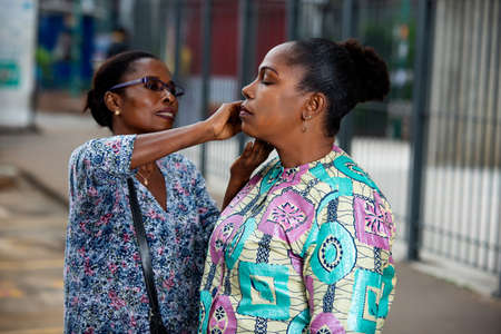 beautiful adult woman getting makeup done by professional make-up artist outdoors on the streetの写真素材