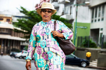 beautiful businesswoman wearing glasses and a beige hat walking down the streetの写真素材
