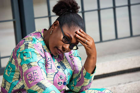 mature woman sitting on stairs, thoughtful outdoors in the streetの写真素材