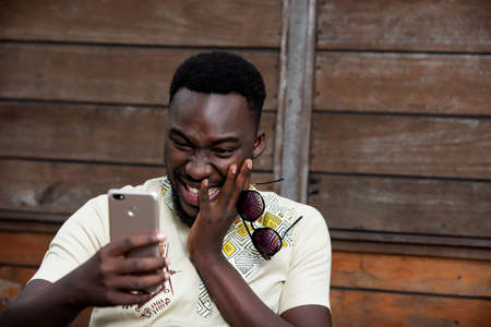 handsome young african man using a mobile phone while being smilingの写真素材