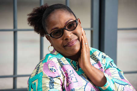 beautiful mature woman wearing eyeglasses and touching cheek with hand and looking at camera smilingの写真素材