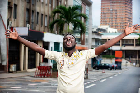 handsome young man, standing the camera, looks ahead, looking up with his hands up, enjoys the new dayの写真素材