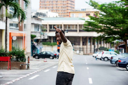 handsome young man walking outdoors in the street and pointing fingersの写真素材