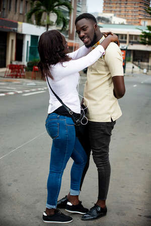 young couple standing outdoors embracing and smiling.の写真素材