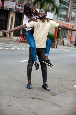 young man carrying his girlfriend on the back and looking at her smiling.の写真素材