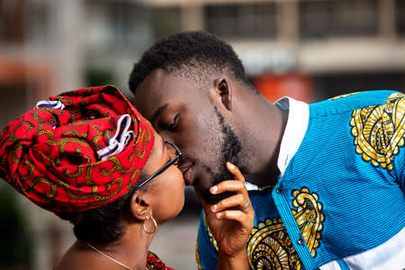 beautiful mature woman in traditional clothes standing outdoors kissing her husband.の写真素材