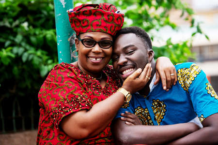 portrait of young man and woman hugging on the street and looking at camera smilingの写真素材