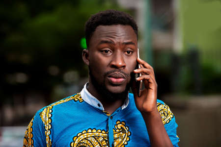 young man in traditional dress standing outdoors communicating with angry look.の写真素材
