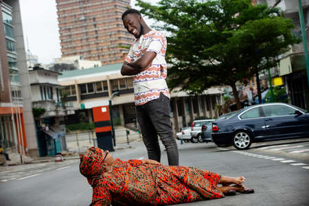 young man standing in the street and his wife lying on the floor look at each other smiling.の写真素材