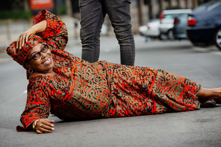 young man standing in the street and his wife sitting on the floor while both looking at the camera smiling.の写真素材