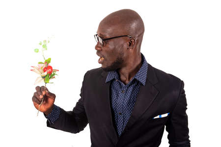 handsome smiling young man wearing black jacket and glasses standing sideways and holding a bouquet of flowers; get ready for an appointment with his girlfriend. Valentine's Day. Mothers' Dayの写真素材
