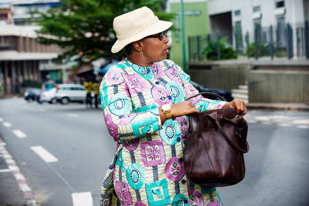 beautiful adult businesswoman wearing a hat and walking down the street looking sidewaysの写真素材