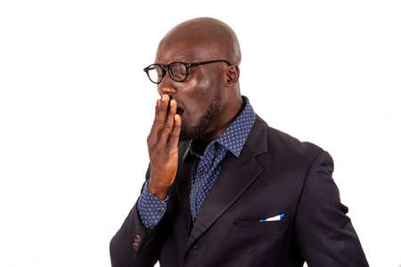 young handsome businessman standing in suit on white background exhausted yawning going covering mouth with hand.の写真素材