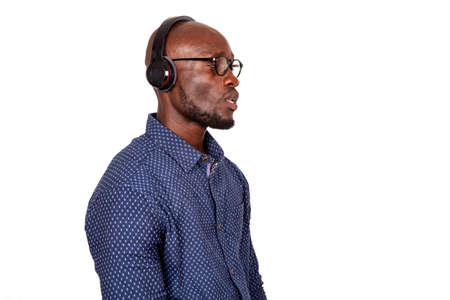 Serious handsome adult man wearing eyeglasses and listening to music with headphones looking sidewaysの写真素材