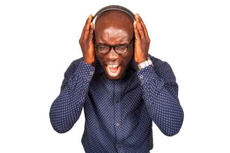 Handsome young man singing hipster listens to music with headphones and screaming at studio
