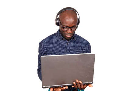 a handsome businessman standing on a white background working with laptop and listening to music using headphones while smilingの写真素材