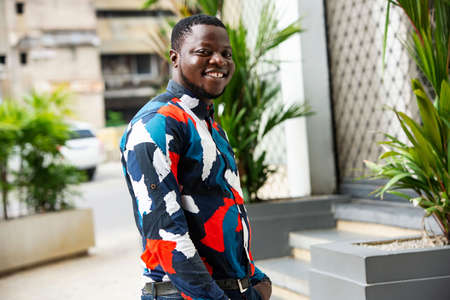 handsome young man standing outdoors in the street posing and looking at camera smilingの写真素材