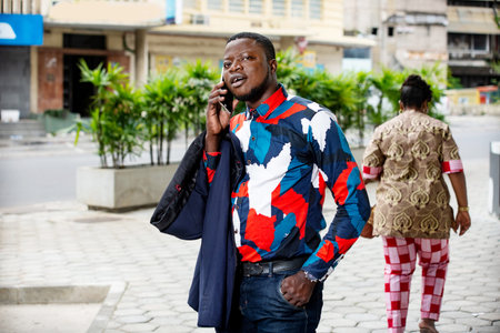 handsome businessman standing outdoors going to communicate on mobile phone smiling