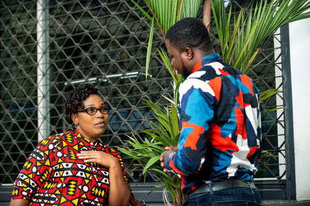 beautiful adult woman standing and talking outdoors with young manの写真素材