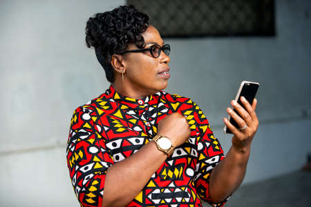 beautiful mature woman in traditional dress sitting outdoors looking at cell phone smilingの写真素材